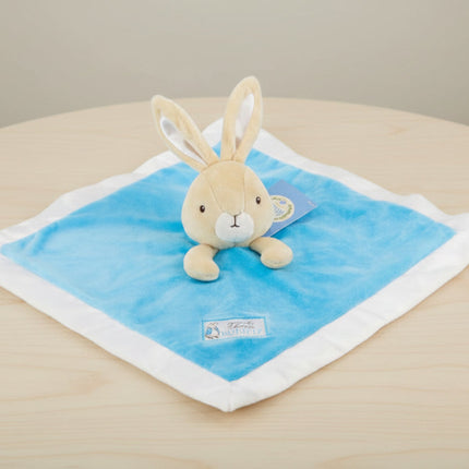 Plush toy rabbit on a blue blanket with a white border on table