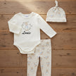 Peter Rabbit Baby clothing set with name Louis on onesie, pants, and hat on a wooden board