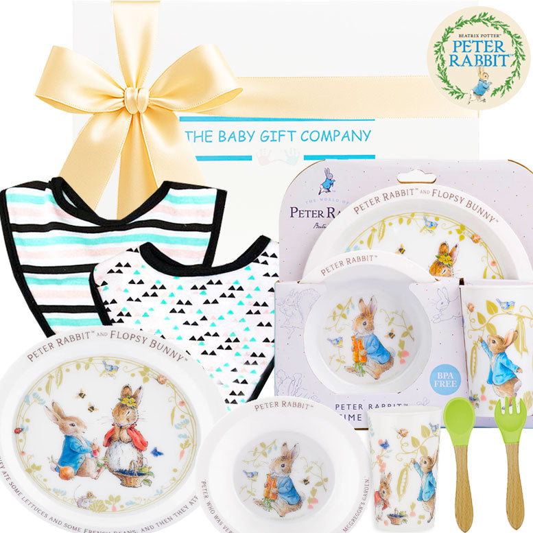 Children's dinner set with 'Peter Rabbit' theme, including plates, cup, and bib, branded by The Baby Gift Company.