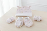 Baby hat, mittens, and booties set with 'XO' and heart patterns on a table