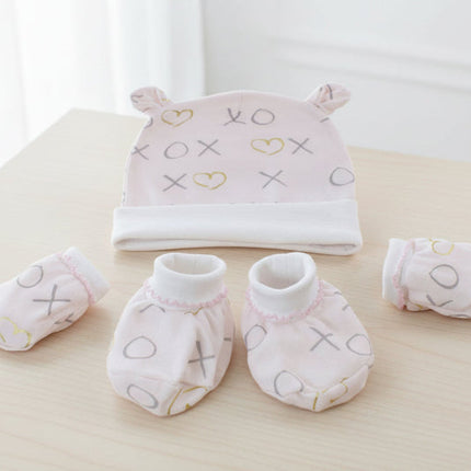 Baby hat, mittens, and booties set with 'XO' and heart patterns on a table