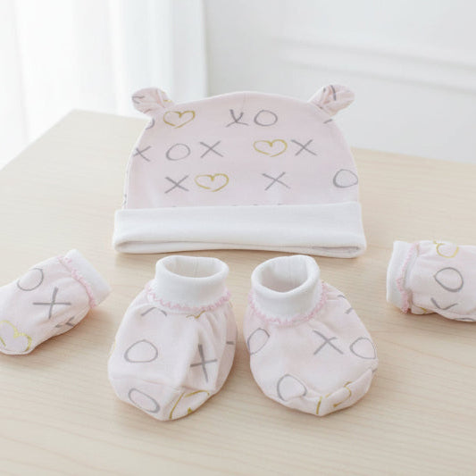 Baby hat, mittens, and booties set with 'XO' and heart patterns on a table