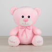 Pink teddy bear with a bow tie on a table background