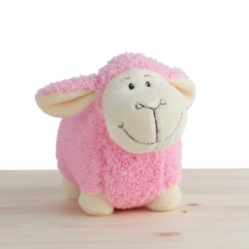 Pink plush toy sheep on a table background