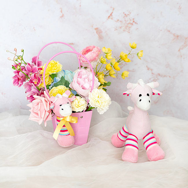 Pink Easter basket with flowers and a plush bunny on a light background