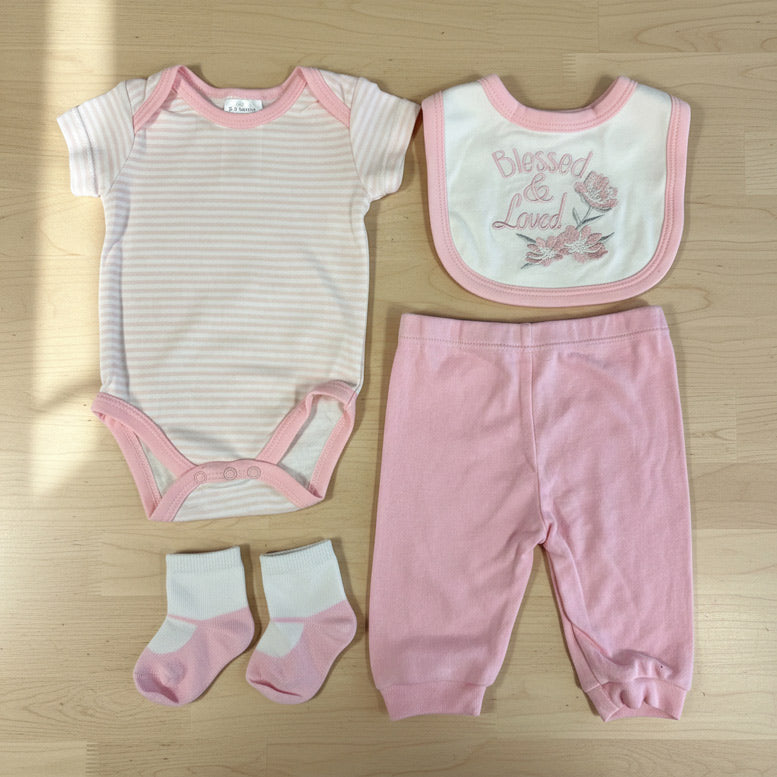 A collection of baby girl pink clothing on light wood background