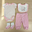 A collection of baby girl pink clothing on light wood background