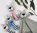 Three plush kangaroo toys with striped legs and a blanket on a white background