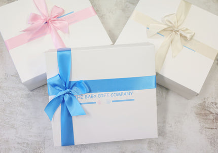 Gift boxes with satin ribbon and the baby gift company logo on a textured surface