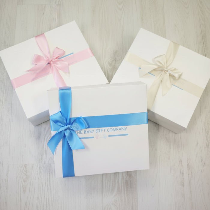 Gift boxes with satin ribbon and the baby gift company logo on a textured surface