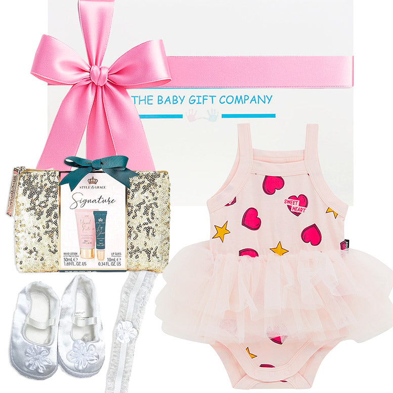 Baby gift set with pink onesie, shoes, and other items from The Baby Gift Company.
