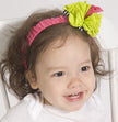 Child wearing a colorful headband with a large bow on a white background