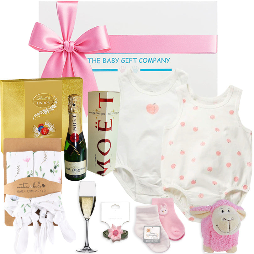 Collection of luxury  baby gift items including a onesie, bottle, and toys with a branded box from The baby gift company