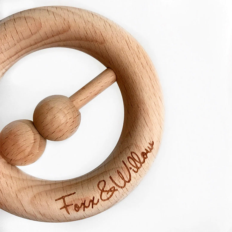 Wooden teething ring with engraved text on a white background