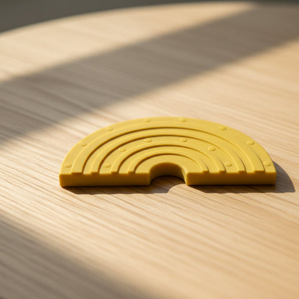 Yellow silicone toy with rainbow pattern on a table background