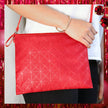 Red geometric patterned pouch held by a person against a white background