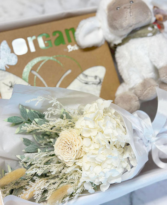 Bouquet of white flowers with a plush toy and box in the background