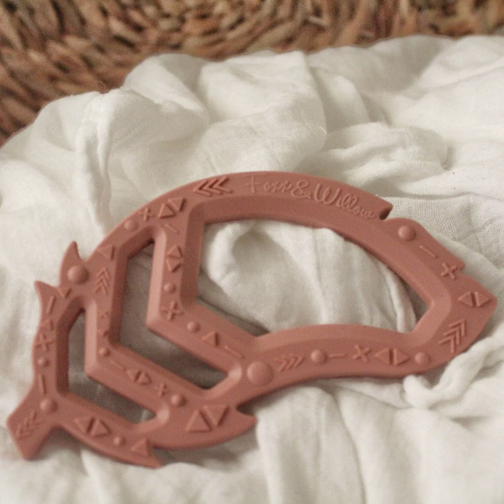 rose pink feather teether toy on fabric