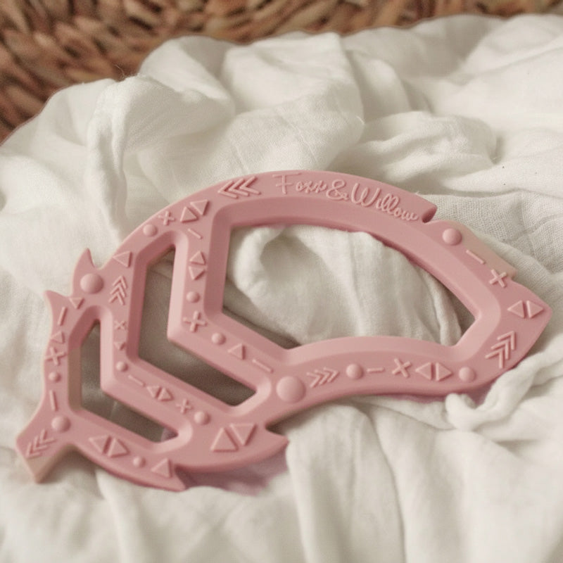 Rose pink feather teether baby toy on white fabric