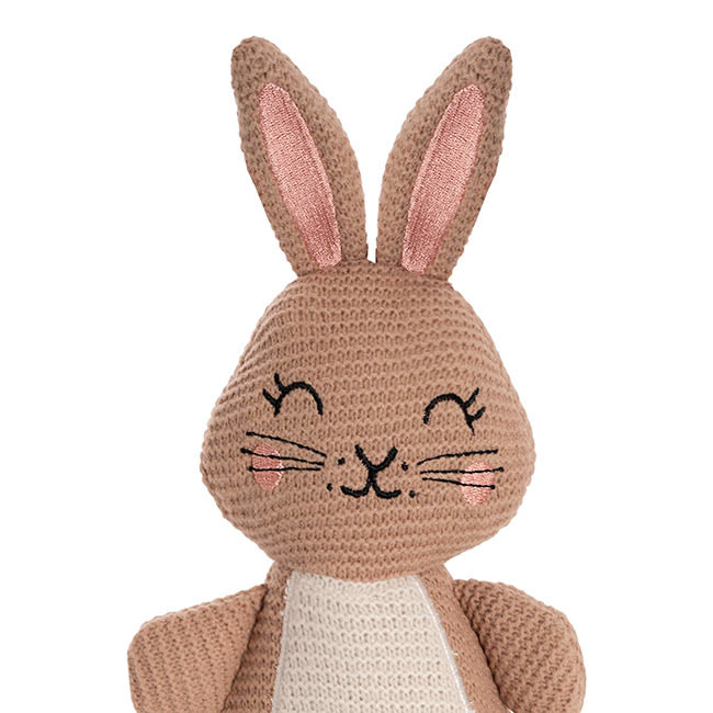 Knitted brown bunny toy with pink inner ears on a white background