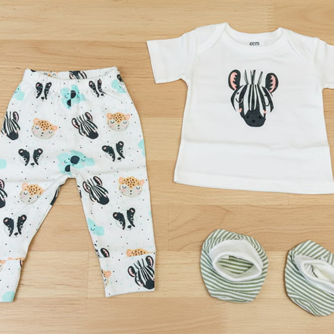 Baby leggings with animal pattern, white shirt with black design, and two green booties on a white background