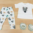 Baby leggings with animal pattern, white shirt with black design, and two green booties on a white background