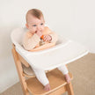 Baby eating a carrot whilst wearing a bib in a high chair