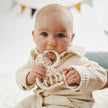 Baby holding a teething toy with a blurred background