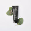 Sukin for Men Facial Scrub tube with eucalyptus leaves on a white background