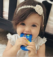 Child with a blue toy in their mouth wearing a decorative headband.