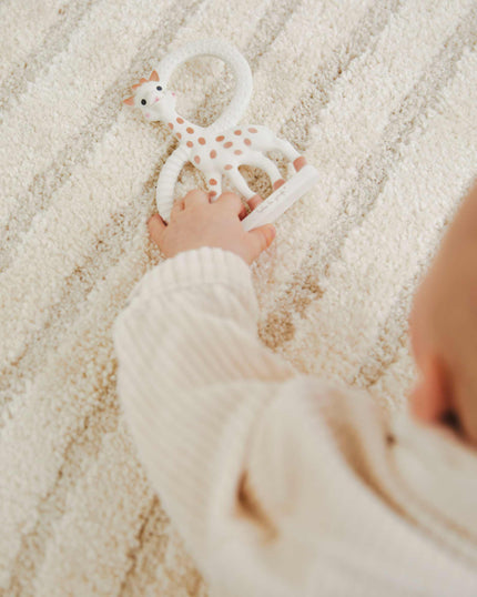 Child's hand holding a Sophie giraffe teething ring 