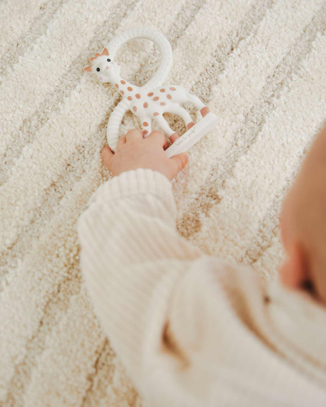 Child's hand holding a Sophie giraffe teething ring 