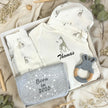 Gift box with giraffe baby clothes on a natural fabric background