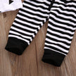 Black and white striped baby leggings on a wooden surface
