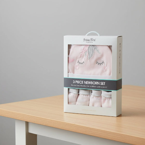 Boxed 3-piece newborn set with baby booties, beanie, and mittens on a table