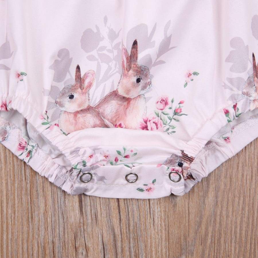 Floral romper with embroidered bunnies on a wooden surface