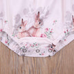 Floral romper with embroidered bunnies on a wooden surface
