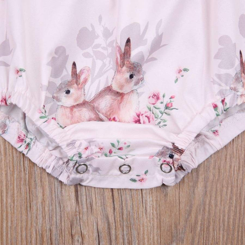Floral romper with embroidered bunnies on a wooden surface