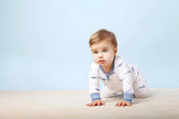 Baby in a white onesie with blue accents on a light blue background