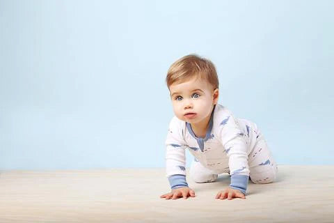 Baby in a white onesie with blue accents on a light blue background
