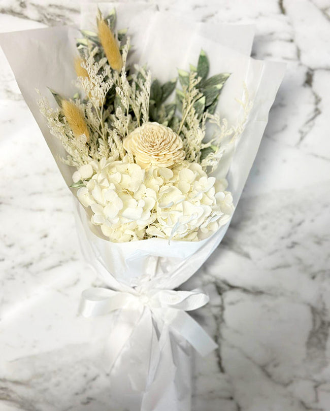 Bouquet of flowers wrapped in white paper on a marble surface