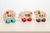 Three wooden animal toys with colorful beads on a white background