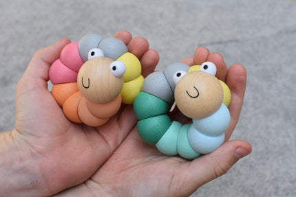 Colorful caterpillar-shaped toys held in a hand against a neutral background