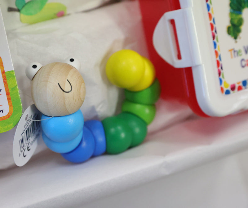 Colorful wooden toy caterpillar with a smiling face on a shelf.